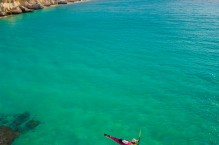 Sea kayaker paddling below cliff on Isla Carmen, Sea of Cortez, Baja, Mexico.