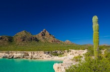 Sea kayakers paddling below cliff on Isla Carmen, Sea of Cortez, Baja, Mexico.