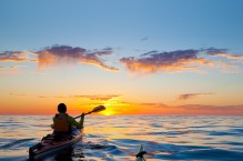 Sea kayaker paddles toward sunrise, Sea of Cortez, Baja, Mexico.