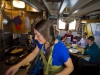 Home Shore chef preparing omlettes in the galley, with some satified guests.