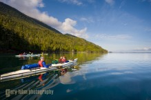 Sea kayakers underway along the Vancouver Island shore. Johnstone Strait, British Columbia, Canada. (MR)