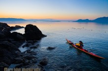 Woman sea kayaker paddling at dawn at Doe Island, San Juan Islands, Washington State.(MR)