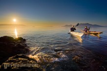 Two women sea kayakers paddling at dawn at Doe Island, San Juan Islands, Washington State.(MR)