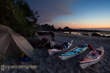 Sea kayaks and tent at kayaker camp, with crescent moon at sunset, at Toleak Point on the Olympic Coast, Olympic National Park, Washington State.