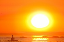 Sea kayaker paddling into big sun sunset, Toleak Point, Olympic National Park, Washington State.