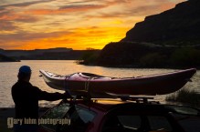 Man unloading sea kayak from car at dawn, Alkili Lake, Washington State